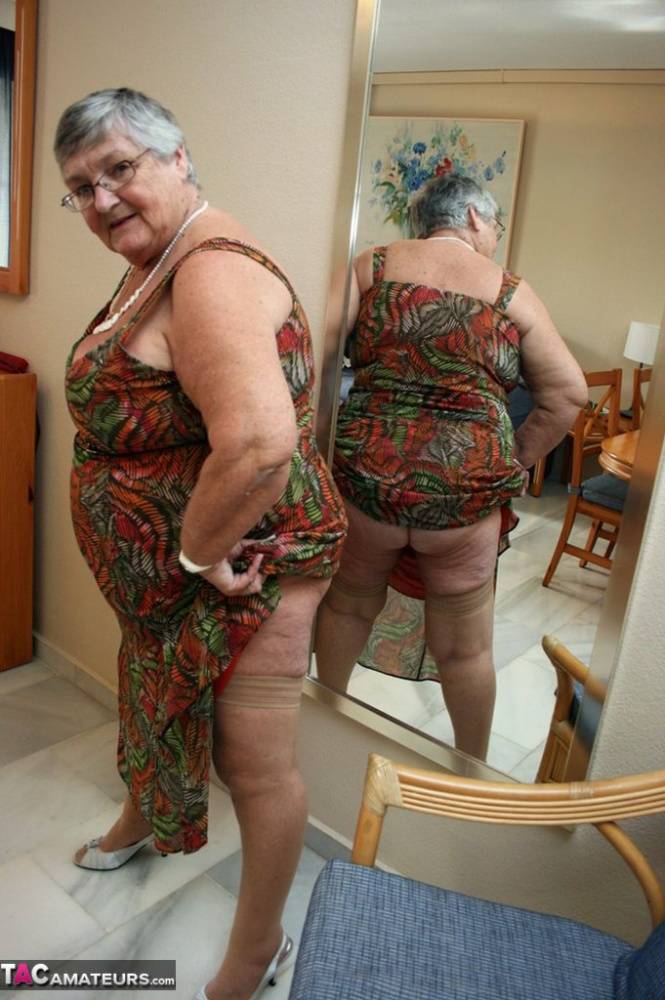 Silver haired granny Grandma Libby exposes her obese figure afore a mirror | Photo: 729770