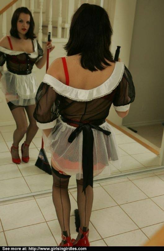 Brunette babe in stockings and maid uniform posing in front of the mirror | Photo: 751283