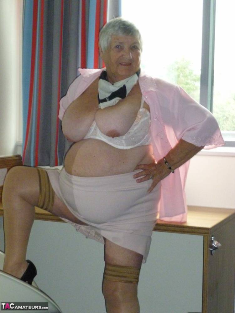 Obese old woman Grandma Libby lays her floppy tits on a desk while undressing | Photo: 779931