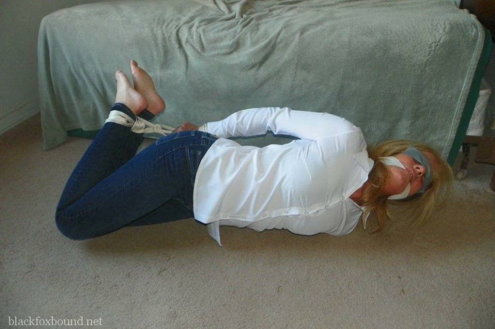 Blonde woman is cleave gagged and hogtied in a white blouse and blue jeans | Photo: 833821