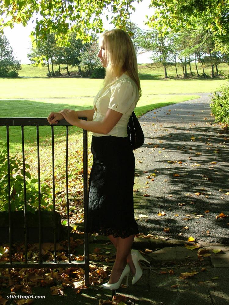 Clothed blonde Iona shows off her white stilettos in a long skirt by a park - #14