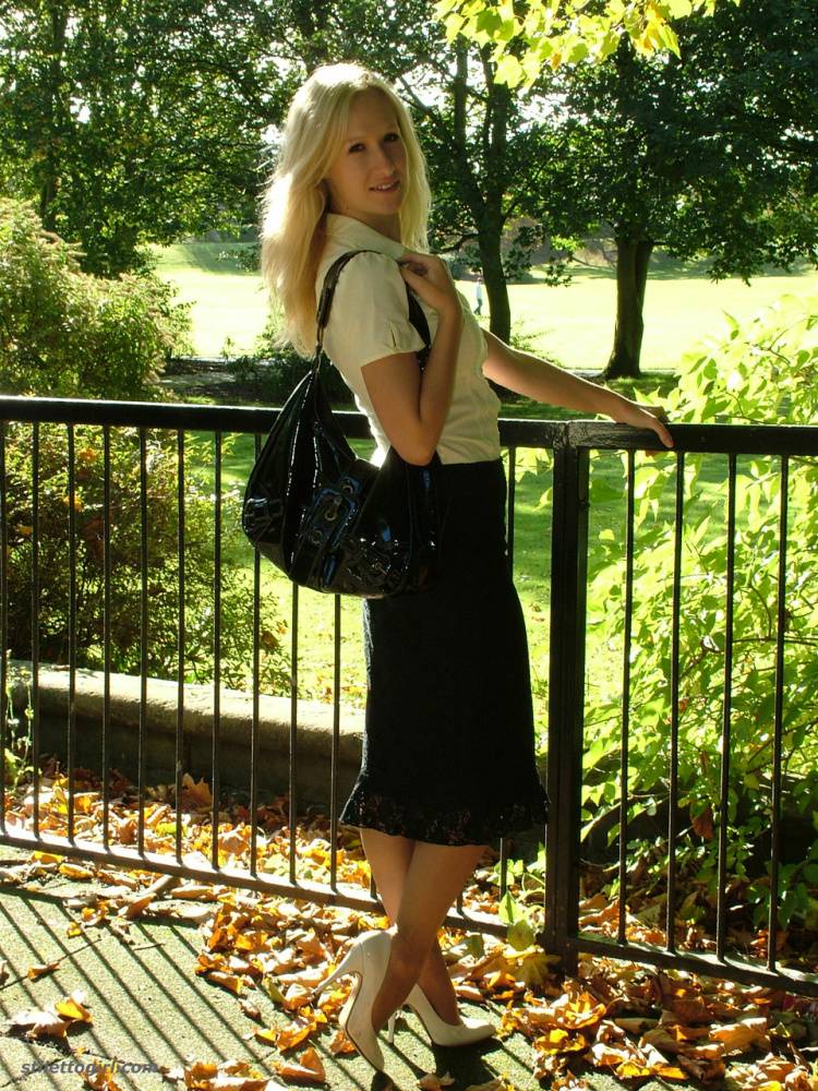 Clothed blonde Iona shows off her white stilettos in a long skirt by a park - #9