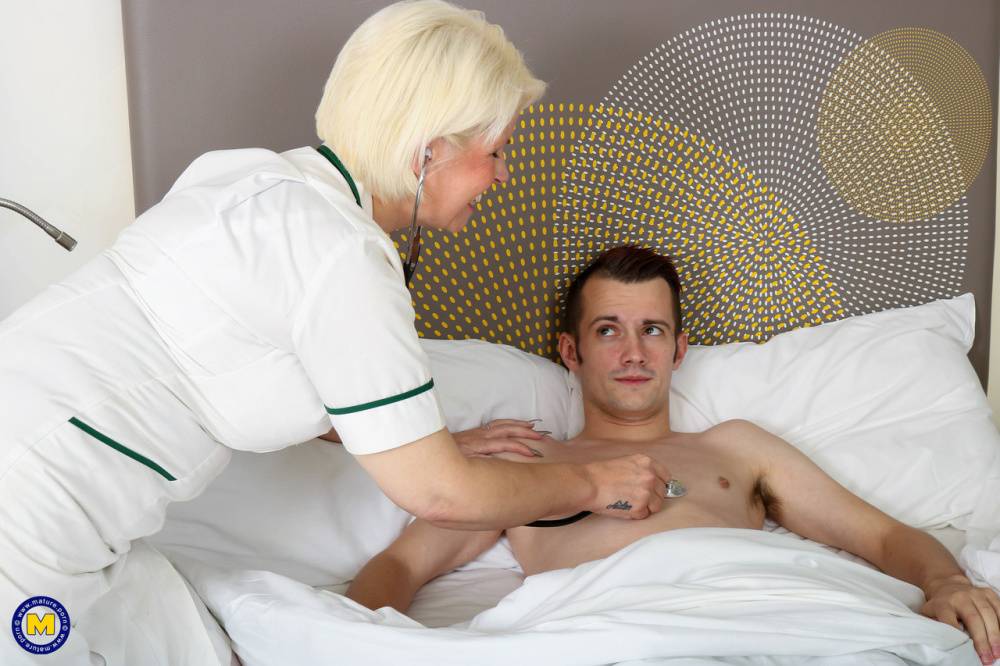Mature nurse with blonde hair seduces a man while he's ill in bed | Photo: 1475398