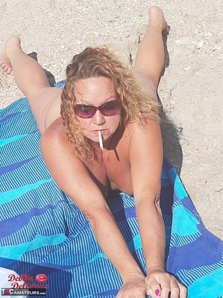Older amateur Debbie Delicious smokes while sunbathing in the nude on a beach - #12