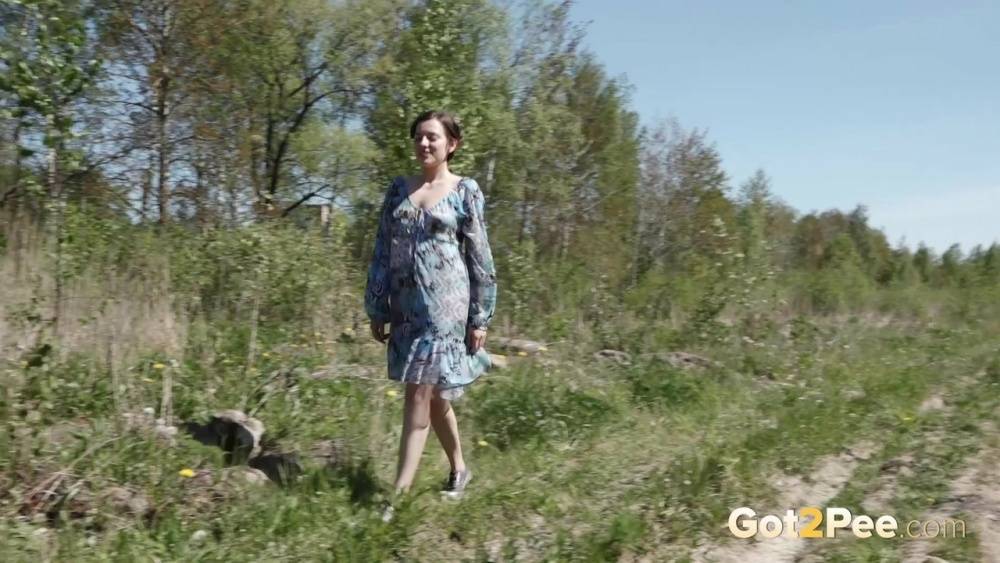 Clothed woman Sasha S hitches up her dress to take a pee on a rock | Photo: 1556917
