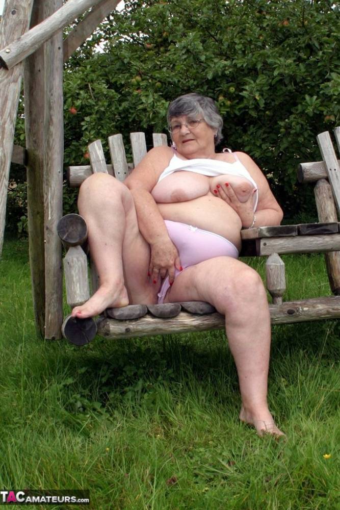 Old British woman Grandma Libby exposes her boobs on a backyard bench swing | Photo: 1585357