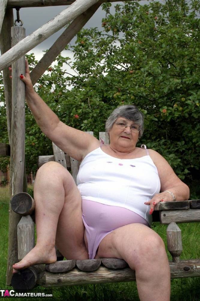 Old British woman Grandma Libby exposes her boobs on a backyard bench swing | Photo: 1585358