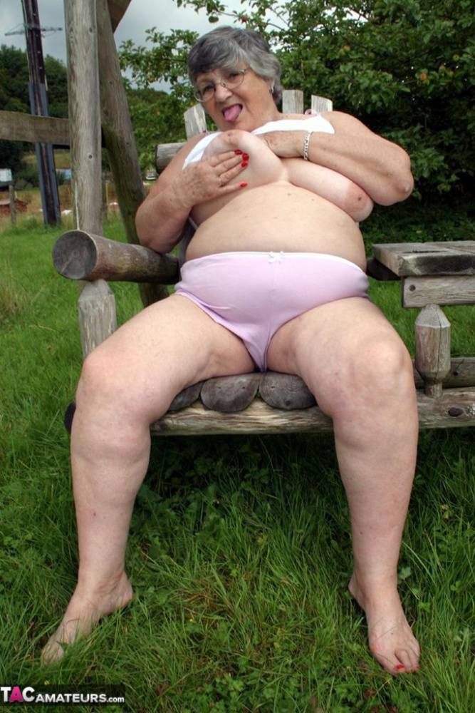 Old British woman Grandma Libby exposes her boobs on a backyard bench swing | Photo: 1585364