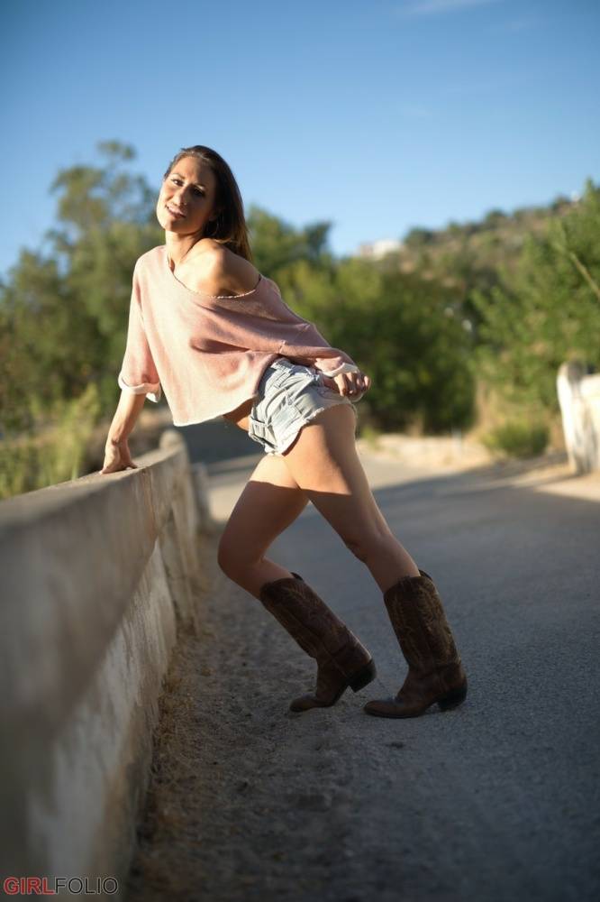 Solo model Jess West walks along a road in nothing more than her cowgirl boots | Photo: 1601933