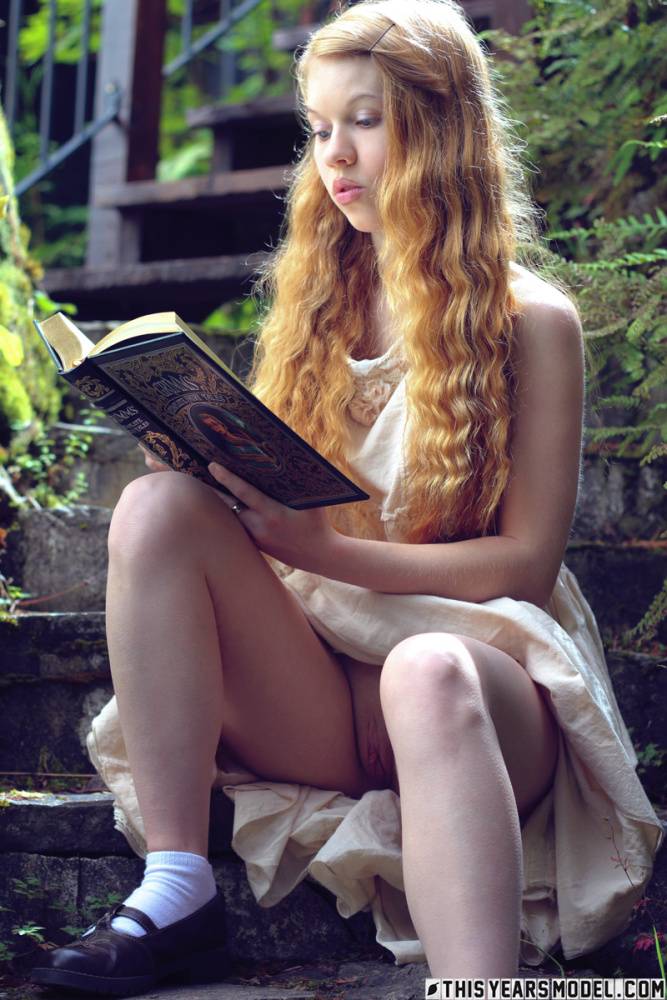 Young redhead Dolly Little exposes herself on garden steps while reading | Photo: 1649849