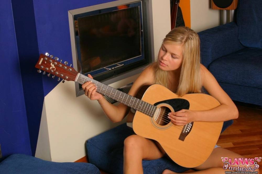 Blonde teen strums a 12 string guitar while getting totally naked | Photo: 1668521