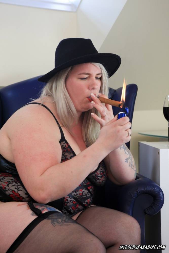 Tatted BBW smokes a cigar while releasing breasts from lingerie in a hat | Photo: 1675791