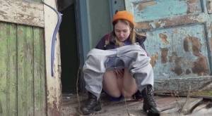 Cute girl pulls down jeans for an urgent piss on the steps of an old building on galphoto.com