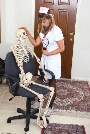 Sexy nurse Christy James peels her white uniform to facesit on a skeleton on galphoto.com