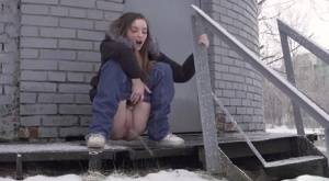 White girl pulls down her jeans to pee in the snow behind a building on galphoto.com