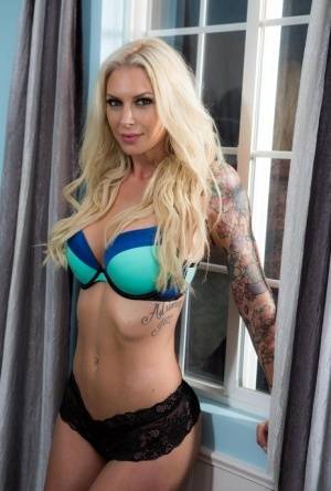 Tattooed MILF pornstar Brooke peels off bra & black lace panties to pose nude